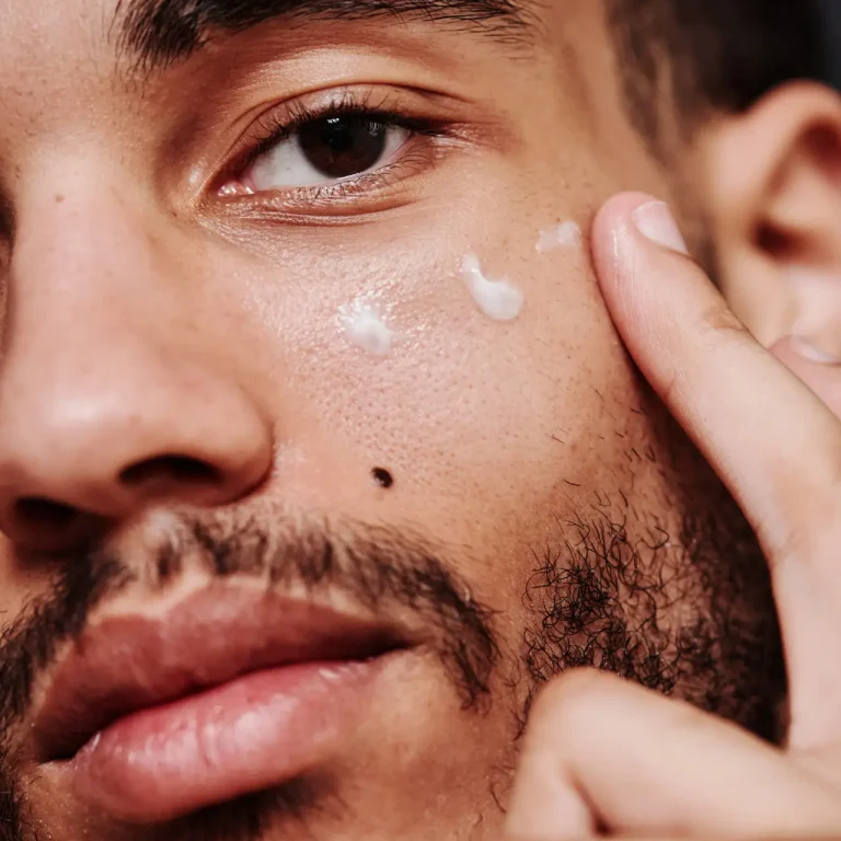 Close-up of young mixed race man applying cream on his face
